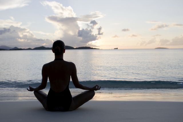 woman practicing yoga at a beach during sunset